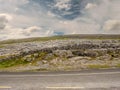 Empty road in Burren National park, Ireland, Rough stone terrain, Traditional stone fence. Cloudy sky in the background Royalty Free Stock Photo