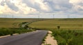 Empty road with curves and fields with beautiful fluffy clouds in the sky. Royalty Free Stock Photo