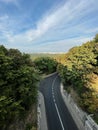 Empty road through a dense forest and a city in the distance Royalty Free Stock Photo