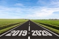 Empty road in a green field with 2019-2020 written