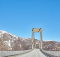 Empty road in the mountains against a blue sky with copy space. Deserted highway crossing in the cold snowy and grey Royalty Free Stock Photo