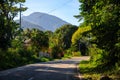 Empty road in tropical island. Summer roadside with mountain and green forest. Motorbike travel in remote location Royalty Free Stock Photo