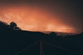 Empty road with yellow indicator lines with an orange sunset sky in the horizon