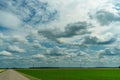 An empty roadway outside the city passes by agricultural fields. A highway with a new asphalt surface on the background of fluffy