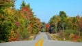 Empty rolling road running past the scenic forest changing colors in autumn. Royalty Free Stock Photo