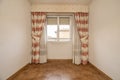 Empty room with aluminum and glass windows, dark stoneware floors and curtains with sheers