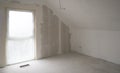 Empty attic room,French window,concrete floor,sanded wall for priming.Niche for built-in heating con.Copy space Royalty Free Stock Photo