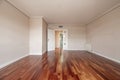 An empty room double folding door made of white lacquered wood and matching skirting boards with jatoba wood parquet floors