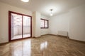 Empty room, French oak parquet floors laid in a herringbone pattern, recently varnished, with aluminum sliding doors with exit