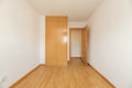 Empty room with oak colored wooden built-in wardrobe with matching flooring, access doors, wooden baseboards and plain white walls Royalty Free Stock Photo