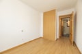 Empty room with oak colored wooden built-in wardrobe with matching flooring and plain white walls Royalty Free Stock Photo