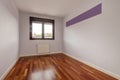 Empty room with reddish wooden flooring, smooth walls painted in light fuchsia and brown anodized aluminum window