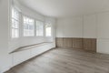 An empty room in a single-family house with a wall with white aluminum windows with a bench underneath with white drawers taking Royalty Free Stock Photo