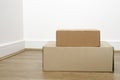 Empty room with stack of cartons: moving house concept. Moving in concept. Two different size boxes  on the laminate floor in the Royalty Free Stock Photo
