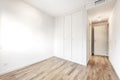 Empty room with three-section built-in wardrobe, white paint, parquet floors