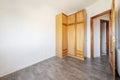 An empty room with a three-section wooden wardrobe in one corner with chests on the mezzanines and drawers in the basement