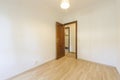 Empty room with varnished sapele wood door, ceiling lamp and laminate flooring
