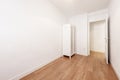Empty room with white cabinet, white walls and laminated oak flooring