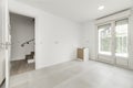 Empty room with white painted walls, white wooden skirting boards, doors leading to a white aluminum patio on the ground floor of Royalty Free Stock Photo