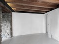 an empty room with wooden beamed ceiling and resin floor