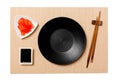 Empty round black plate with chopsticks for sushi, ginger and soy sauce on brown sushi mat background. Top view with copy space Royalty Free Stock Photo