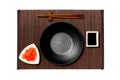 Empty round black plate with chopsticks for sushi, ginger and soy sauce on dark bamboo mat background. Top view with copy space Royalty Free Stock Photo