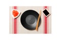 Empty round black plate with chopsticks for sushi and soy sauce, ginger on sushi mat background. Top view with copy space for you Royalty Free Stock Photo