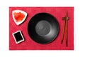 Empty round black plate with chopsticks for sushi and soy sauce, ginger on red mat sushi background. Top view with copy space for Royalty Free Stock Photo