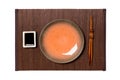 Empty round brown plate with chopsticks for sushi and soy sauce on dark bamboo mat background. Top view with copy space for you Royalty Free Stock Photo