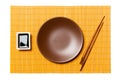 Empty round brown plate with chopsticks for sushi and soy sauce on yellow bamboo mat background. Top view with copy space for you Royalty Free Stock Photo