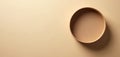 Empty round cardboard gift box sits on plain beige surface. Soft light casts shadow, highlighting its minimalist shape and Royalty Free Stock Photo