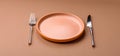An empty round ceramic plate, knife, and fork as a dining table setting. An empty plate Royalty Free Stock Photo