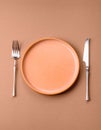 An empty round ceramic plate, knife, and fork as a dining table setting. An empty plate Royalty Free Stock Photo