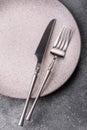 An empty round ceramic plate, knife, and fork as a dining table setting. An empty plate Royalty Free Stock Photo