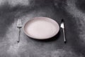 An empty round ceramic plate, knife, and fork as a dining table setting. An empty plate Royalty Free Stock Photo
