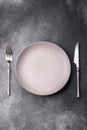 An empty round ceramic plate, knife, and fork as a dining table setting. An empty plate Royalty Free Stock Photo