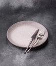An empty round ceramic plate, knife, and fork as a dining table setting. An empty plate Royalty Free Stock Photo
