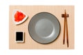 Empty round gray plate with chopsticks for sushi and soy sauce, ginger on brown sushi mat background. Top view with copy space for Royalty Free Stock Photo