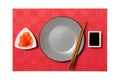 Empty round gray plate with chopsticks for sushi and soy sauce, ginger on red mat sushi background. Top view with copy space for Royalty Free Stock Photo