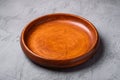 Empty round handcrafted brown wooden plate on stone concrete background