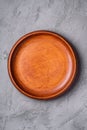 Empty round handcrafted brown wooden plate on stone concrete background