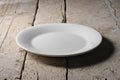 Empty white round plate on rough wooden table Royalty Free Stock Photo