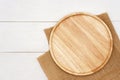 Empty round wooden plate with rustic brown burlap cloth on white wooden table. Royalty Free Stock Photo