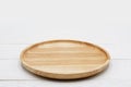 Empty round wooden plate on white wooden table.