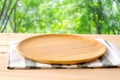 Empty round wooden tray and napery on table over blur tree background, for food and product display montage, template Royalty Free Stock Photo