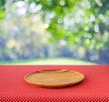 Empty round wooden tray on red polka dot tablecloth over blur tr