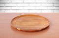 Empty round wooden tray on table over white brick wall background Royalty Free Stock Photo