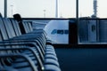 Empty row of seats at departure area with airplane connected to finger dock on background Royalty Free Stock Photo