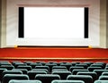 Empty rows of comfortable seats with big screen with white clipping path in cinema or theater Royalty Free Stock Photo