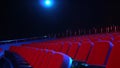 Empty rows of seats in cinema hall. Empty movie theater with red seats in darkened room with projector light on Royalty Free Stock Photo